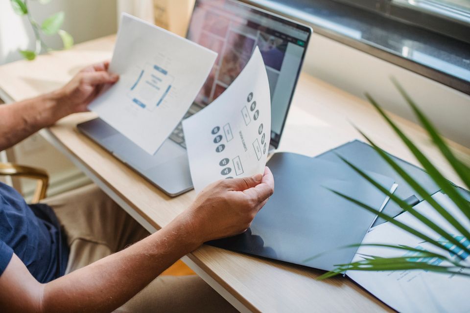 Una persona revisa documentos junto a su computador